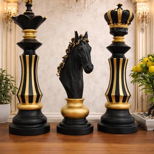 Könnte beinhalten: Dekoratives Schachspiel mit schwarzen und goldenen Figuren. Das Set enthält zwei Schachfiguren mit kronenförmigen Spitzen, eine Pferdekopf-Büste und Figuren mit goldenen Akzenten. Die Schachfiguren werden auf einer Holzoberfläche präsentiert.