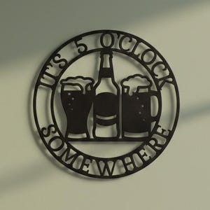 May include: Black metal wall art featuring the text "IT'S 5 O'CLOCK SOMEWHERE" around a beer bottle and two beer glasses. The circular sign is ideal for a pub or kitchen.