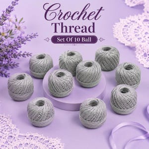 May include: A set of 10 balls of light gray crochet thread arranged on a circular platform. The text Crochet Thread Set Of 10 Ball is printed in dark purple above the items. The scene features lavender sprigs and white lace accents.