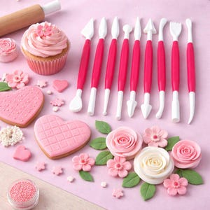 May include: A selection of pink cake decorating tools with white tips and pink handles, alongside decorated cupcakes, heart-shaped biscuits, and floral decorations on a pink surface. A wooden rolling pin is also present.