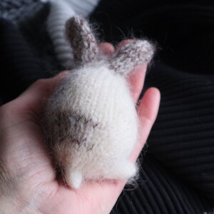 Puede incluir: Un juguete de conejo de peluche blanco y marr&oacute;n tejido con una textura esponjosa.