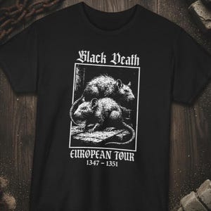 Puede incluir: Camiseta negra con un diseño gráfico blanco de dos ratas, las palabras "Black Death" y "European Tour 1347-1351" en fuente gótica. El diseño es una ilustración de estilo vintage.