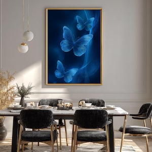 May include: A framed artwork featuring three blue butterflies against a dark blue background. The butterflies have a glowing effect, and the frame is gold. The artwork is displayed in a dining room with a marble table and black chairs.