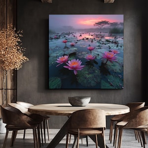 Op de afbeelding: Een canvas print met een serene waterlandschap met roze lotusbloemen. Het kunstwerk toont een levendige zonsondergang met een boom silhouet, waardoor een rustige en kleurrijke scène ontstaat. Het schilderij wordt getoond in een eetkamer.