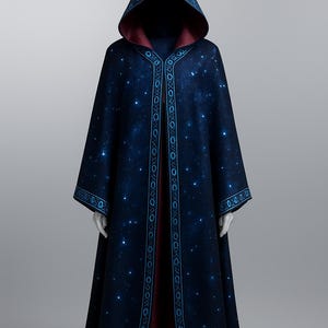 Pode incluir: Uma capa com capuz azul escuro com um design celestial. A capa apresenta um padrão de estrelas e uma borda decorativa em um azul mais claro. O interior do capuz e a parte interna da capa é vermelho escuro.