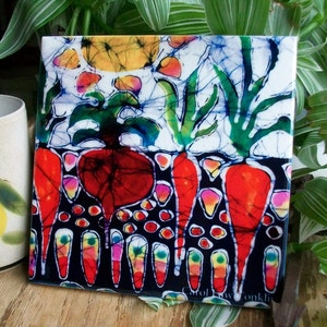 May include: A colorful batik tile featuring a red beet and carrots with a white background and green leaves. The tile is signed "Carol Dawn Conklin".