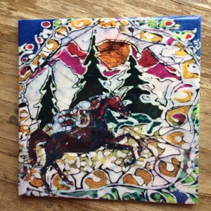 May include: Square ceramic tile with a colorful, artistic design. The image features a running horse in shades of brown and red, set against a backdrop of trees, mountains, and a sun. The border is a mix of colors and patterns.