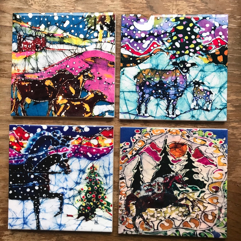 Puede incluir: Cuatro posavasos cuadrados de cer&aacute;mica con ilustraciones coloridas estilo batik. Cada posavasos presenta una escena invernal diferente con animales, incluyendo caballos y ovejas, sobre paisajes nevados con &aacute;rboles y una casa.
