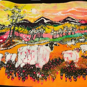 May include: A colorful batik painting depicting a landscape with mountains, trees, and sheep. The sky is a vibrant orange and yellow, with pink and purple clouds. The sheep are white with pink and black markings. The trees are green with white flowers. The mountains are purple and black.