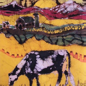 May include: A batik painting of a rural scene, showing a black and white cow grazing. The artwork includes a barn, rolling hills, and a sunset in yellow, red, and green hues, creating a vibrant countryside image.