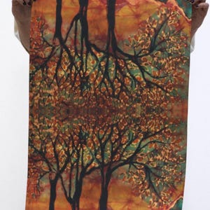 May include: A rectangular textile wall hanging featuring a mirrored batik print of trees with black trunks and branches against a background of orange, yellow, and teal foliage. The design is symmetrical, showing two tree canopies meeting in the center.