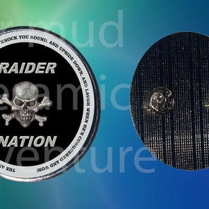 May include: A round, black and silver metal pin with the words "RAIDER NATION" and a skull and crossbones design. The pin has text around the edge that reads "THE AUTUMN WIND IS A RAIDER, PILLAGING JUST FOR FUN. HE'LL KNOCK YOU ROUND, AND UPSIDE DOWN, AND LAUGH WHEN HE'S CONQUERED AND WON!"