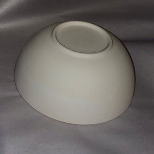 May include: A white, ceramic bowl with a rounded shape and a flat base. The bowl has a smooth, matte finish and is suitable for serving food or as a decorative item. The bowl is empty and appears to be new.