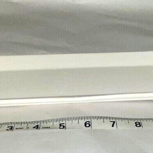 May include: A rectangular, white ceramic serving platter. The platter is approximately 11 inches long and 4 inches wide. It has a slightly raised edge and a clean, minimalist design, suitable for serving appetizers or small dishes.