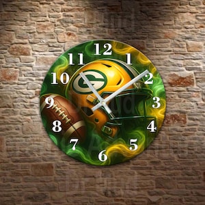 May include: Round wall clock featuring a football helmet and football in green and yellow. The clock face has white numbers and hands. The background has a green and yellow design. The clock is mounted on a brick wall.