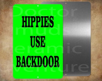 May include: A rectangular metal sign with the text "HIPPIES USE BACKDOOR" in bold black letters on a bright green background. The sign is next to a silver metal sign.