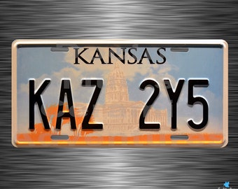 May include: A rectangular license plate with the word "KANSAS" at the top and the letters "KAZ" and numbers "2Y5" below. The background depicts a capitol building and a sunset. The plate has a metallic finish.
