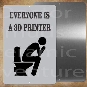 May include: A rectangular metal sign with the text "EVERYONE IS A 3D PRINTER" above a black silhouette of a person sitting on a toilet. The sign is light gray with a brushed metal backing.