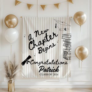 Puede incluir: Una pancarta de graduación a rayas beige con el texto "A New Chapter Begins" y "Congratulations Patrick Class of 2026". La pancarta presenta ilustraciones de un birrete, un diploma y libros. Se muestran globos dorados y blancos.