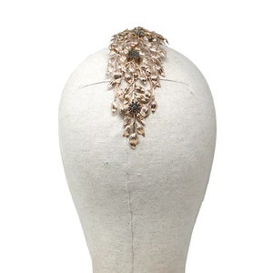 May include: Gold hair comb with a floral design and black rhinestones. The comb is on a white mannequin head.