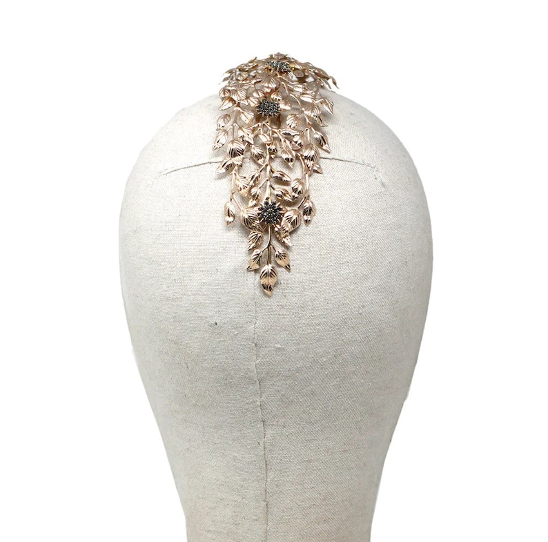 May include: Gold hair comb with a floral design and black rhinestones. The comb is on a white mannequin head.