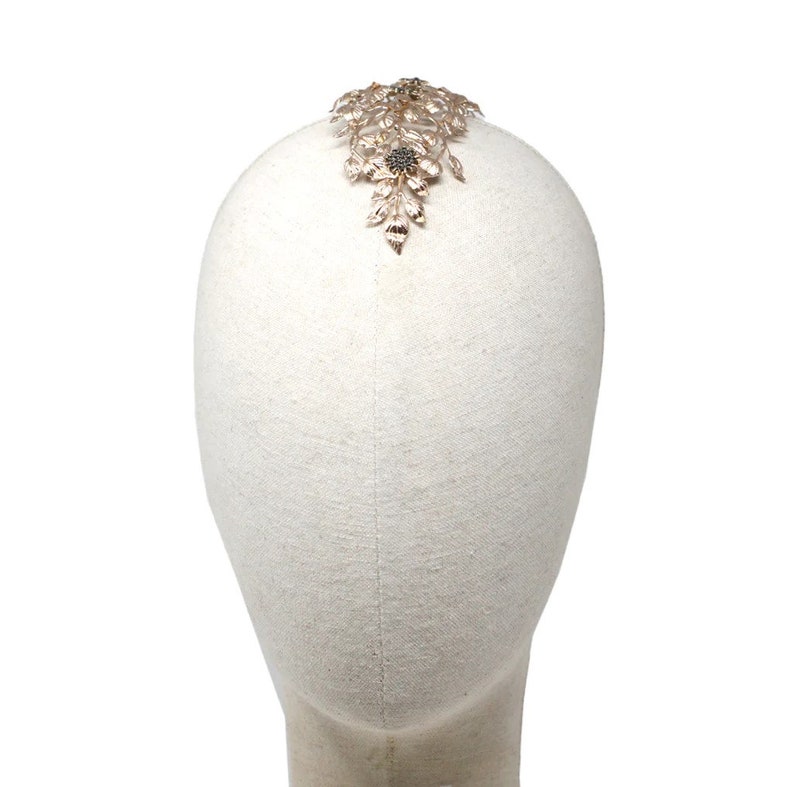 May include: A gold-toned hair comb with a floral design. The comb is on a white mannequin head.