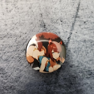 May include: Round button pin featuring an anime-style illustration of a woman with red hair and a blue top. The artwork has a detailed, colorful design with a black background. The pin is a glossy, circular shape.
