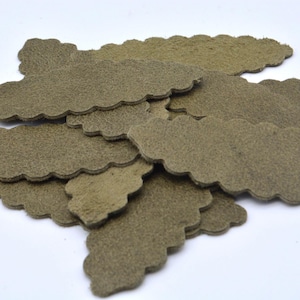 Può includere: Un insieme di pezzi di pelle verde oliva con bordi smerlati. I pezzi hanno una forma irregolare e una superficie strutturata. Sono disposti su uno sfondo bianco.