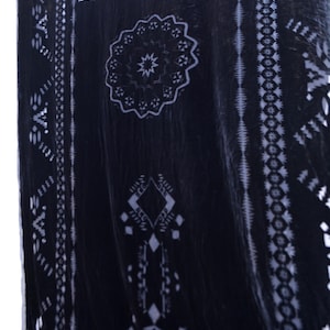 May include: A dark navy blue textile with a white geometric pattern. The design includes a central circular motif and borders with repeating shapes. The fabric appears to be soft and flowing, with a slight sheen.
