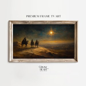 May include: Framed art print depicting three figures on camels traveling towards a bright star in a night sky. The artwork has a warm color palette with a wooden frame. Text at the top reads "PREMIUM FRAME TV ART".