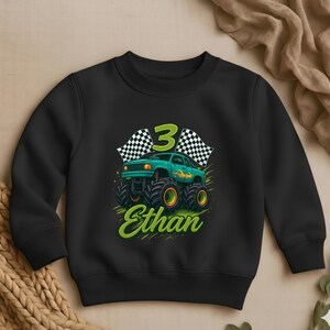 May include: Black sweatshirt with a graphic of a green monster truck with orange wheels, the number 3, and checkered flags. The name "Ethan" is written in green script below the truck.