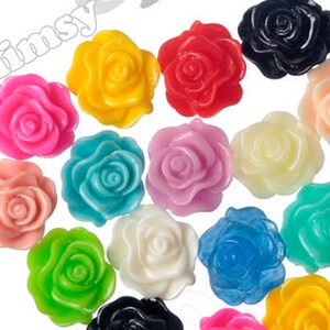 May include: Assortment of colorful plastic flower embellishments. The flowers are in various colors, including pink, red, yellow, blue, green, and white. They are all approximately 1 inch in diameter.