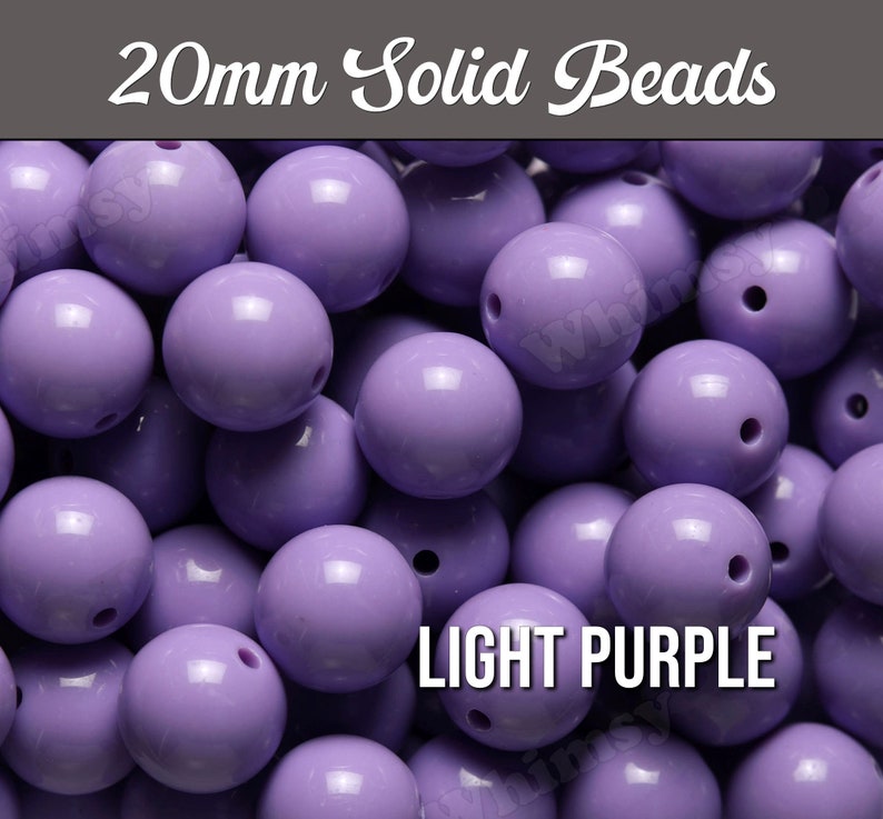 May include: A close-up of a pile of 20mm solid light purple beads. The beads are round and have a smooth, glossy finish.
