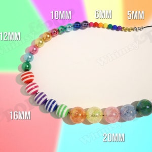 May include: A rainbow-colored beaded necklace with different sized beads, including 5mm, 6mm, 10mm, 12mm, 16mm, and 20mm beads. The beads are made of various materials, including plastic, glass, and metal.