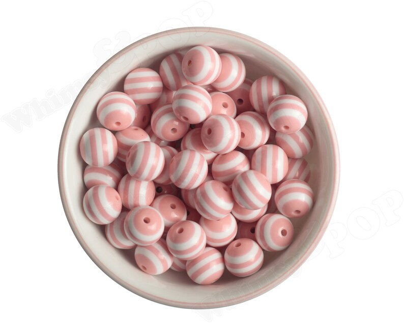 K&ouml;nnte beinhalten: Eine Sch&uuml;ssel gef&uuml;llt mit runden, rosa und wei&szlig; gestreiften Perlen. Die Perlen sind aus Silikon und eignen sich perfekt f&uuml;r die Herstellung von Schmuck oder anderen Bastelarbeiten.