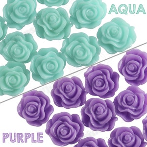 May include: Two rows of plastic rose-shaped embellishments. The top row is aqua blue and the bottom row is purple.