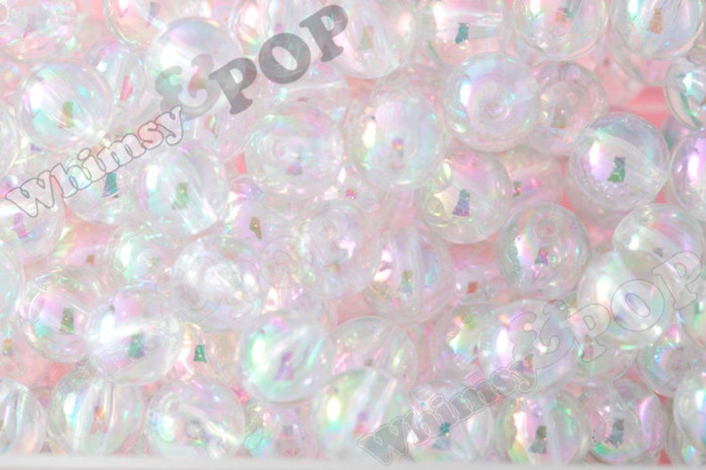 May include: A close-up image of iridescent white round beads. The beads are translucent and have a pearlescent finish.