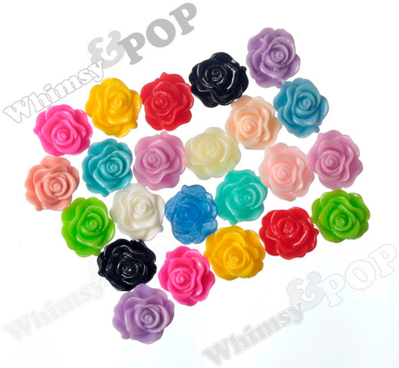 May include: Assortment of colorful plastic flower embellishments. The flowers are in various colors, including pink, red, yellow, blue, green, and white. They are all approximately 1 inch in diameter.