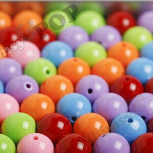 May include: A close-up of a variety of colorful round beads. The beads are made of plastic and have a glossy finish. The colors include red, orange, yellow, green, blue, purple, and pink.