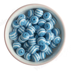 K&ouml;nnte beinhalten: Eine Sch&uuml;ssel gef&uuml;llt mit blauen und wei&szlig;en, runden Perlen mit Streifen. Die Perlen sind aus Kunststoff und haben eine gl&auml;nzende Oberfl&auml;che.