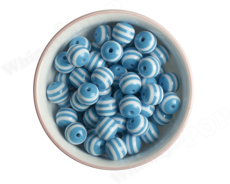 K&ouml;nnte beinhalten: Eine Sch&uuml;ssel gef&uuml;llt mit blauen und wei&szlig;en, runden Perlen mit Streifen. Die Perlen sind aus Kunststoff und haben eine gl&auml;nzende Oberfl&auml;che.