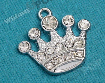 May include: Silver crown charm with clear rhinestones. The crown has a pointed top and a rounded base.