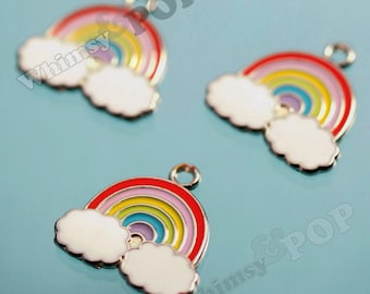 Könnte beinhalten: Drei Metallanhänger in Regenbogenform mit weißen Wolken an beiden Enden. Jeder Anhänger zeigt konzentrische Streifen in roter, gelber und blauer Emaille und besitzt eine kleine kreisförmige Öse an der Oberseite. Der Text Whimsy & POP ist sichtbar.