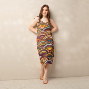 Puede incluir: Vestido hasta la rodilla con un patrón de arcos repetidos en tonos naranja, amarillo, verde y morado. El vestido tiene tirantes finos y una silueta ajustada. El vestido mide aproximadamente 100 cm de largo.
