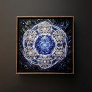 May include: Square framed artwork with a geometric design. It features a central blue crystal-like shape surrounded by interconnected star-like figures. The artwork has a dark blue and white colour scheme, with a wooden frame.
