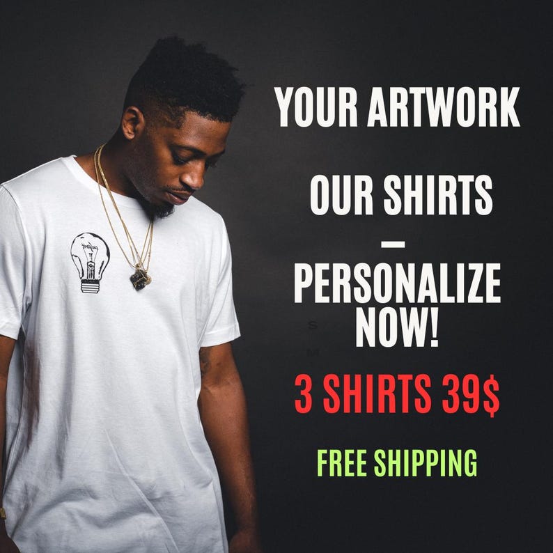 Puede incluir: Una camiseta blanca con un gr&aacute;fico de bombilla negra. El texto de la imagen dice "TU ARTE, NUESTRAS CAMISETAS - &iexcl;PERSONALIZA AHORA!"