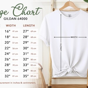 Puede incluir: Una camiseta blanca Gildan 64000 cuelga de un perchero de madera, con una tabla de tallas a la izquierda. La tabla enumera las tallas XS a 5XL, con las medidas de ancho y largo correspondientes en pulgadas y cent&iacute;metros. Flechas indican el ancho y el largo de la camiseta.
