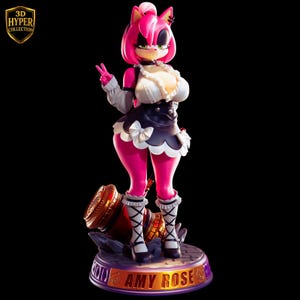 Może przedstawiać: Różowa figurka Amy Rose, postaci z serii Sonic the Hedgehog, w stroju pokojówki. Figurka stoi na podstawie z napisem "AMY ROSE" i logo "3D HYPER COLLECTION". Figurka unosi dwa palce.