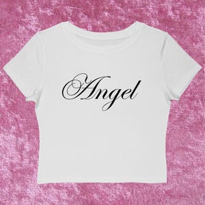 Puede incluir: Taza de cerámica blanca con asa negra y la frase "But First, Coffee" en negro. El fondo borroso sugiere un ambiente acogedor.