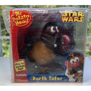 May include: A Mr. Potato Head Darth Tater toy in a clear plastic box. The packaging features the Star Wars logo, the Mr. Potato Head logo, and the text Mix 'n match fun. The toy is a brown potato-shaped figure dressed as Darth Vader.